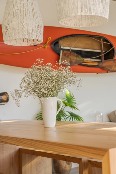 reforma integral en Castelldefels - cocina abierta y detalle de kayak en la pared y mesa de madera - Renew Barcelona