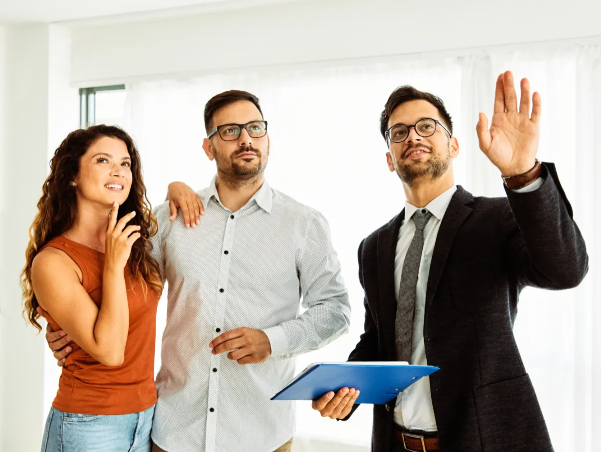 Tasador de inmueble está aconsejando a pareja sobre reformas para incrementar el valor del piso, y la pareja imagina como quedará la reforma una vez terminada (foto conceptual)